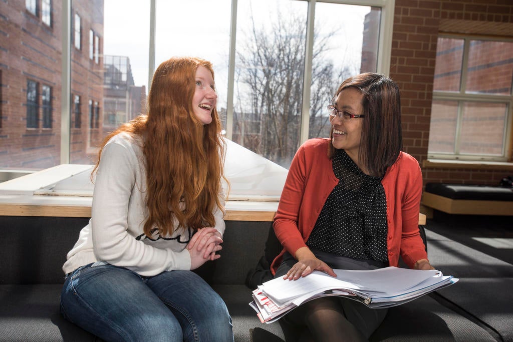 student and advisor sit together looking at a binder