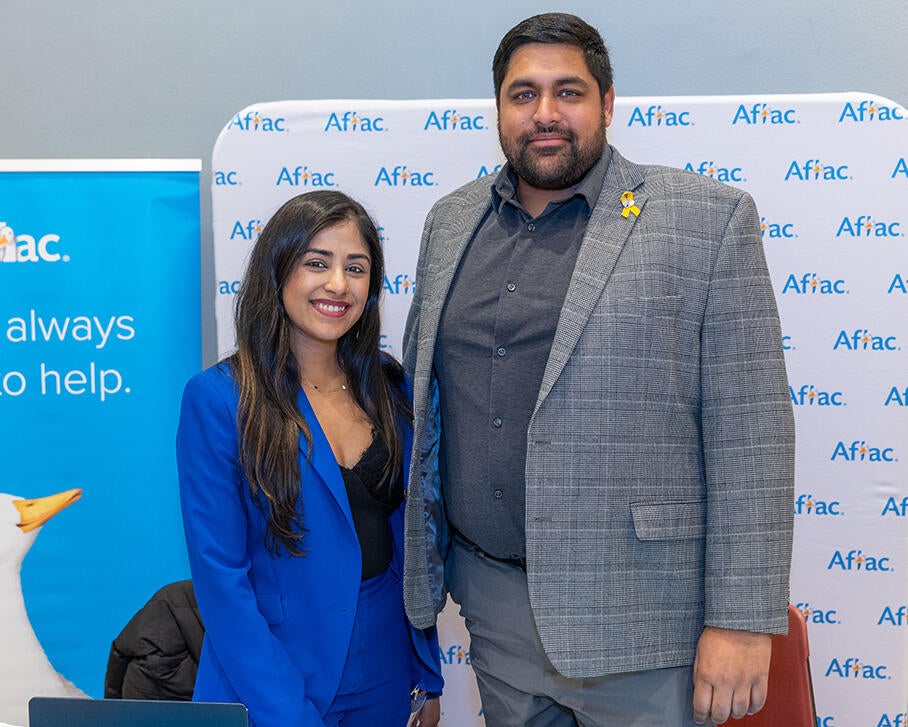 Two AFLAC employers wearing business suits stand shoulder to shoulder smiling at the camera. 