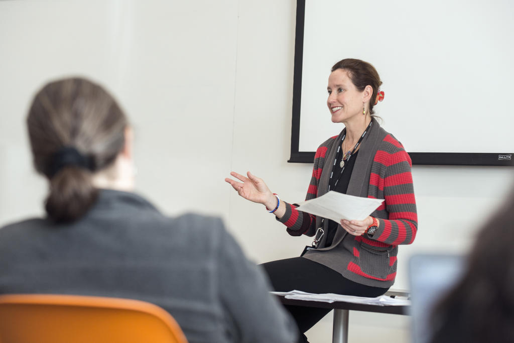 instructor sits on the table at the front of the class