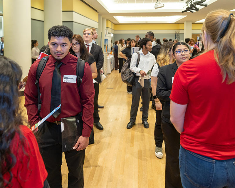 George Mason University students wearing business suits stand in line to speak to recruiters at the Career Fair